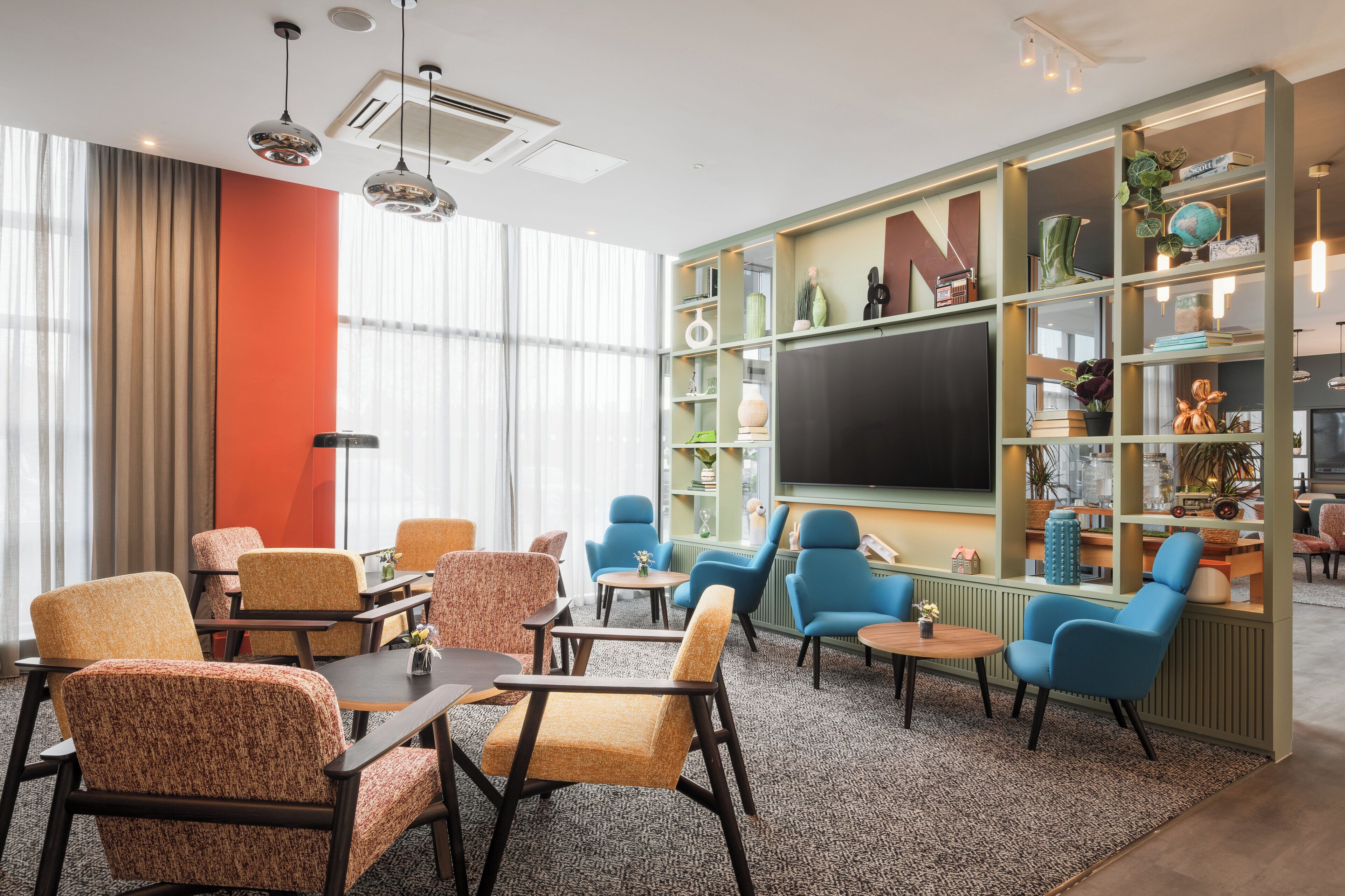 A modern lounge area with comfortable seating, a large bookshelf, and a flat-screen TV.