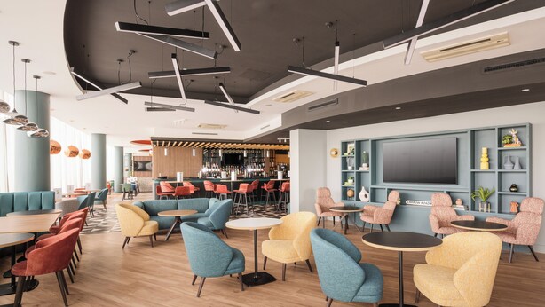 A modern lounge area with seating, a bar, and a large TV screen. - Holiday Inn Norwich City by IHG (Norwich)