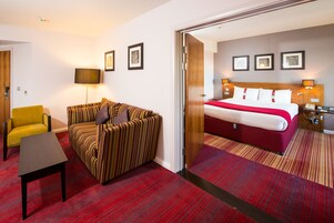 Una habitación de hotel con una cama, un sofá, una silla y una mesita.