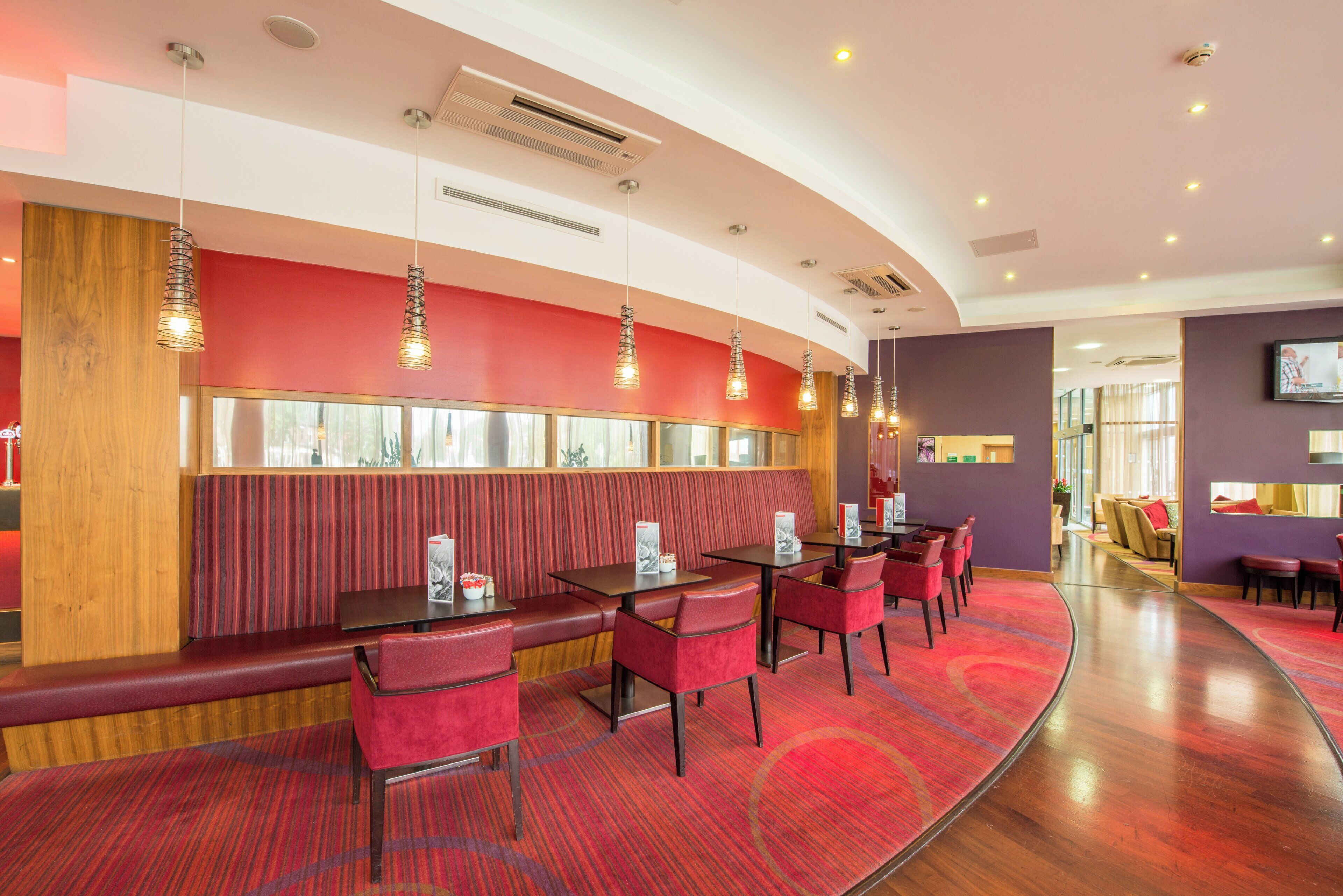 A restaurant with booths and tables, a TV screen, and a patterned carpet.