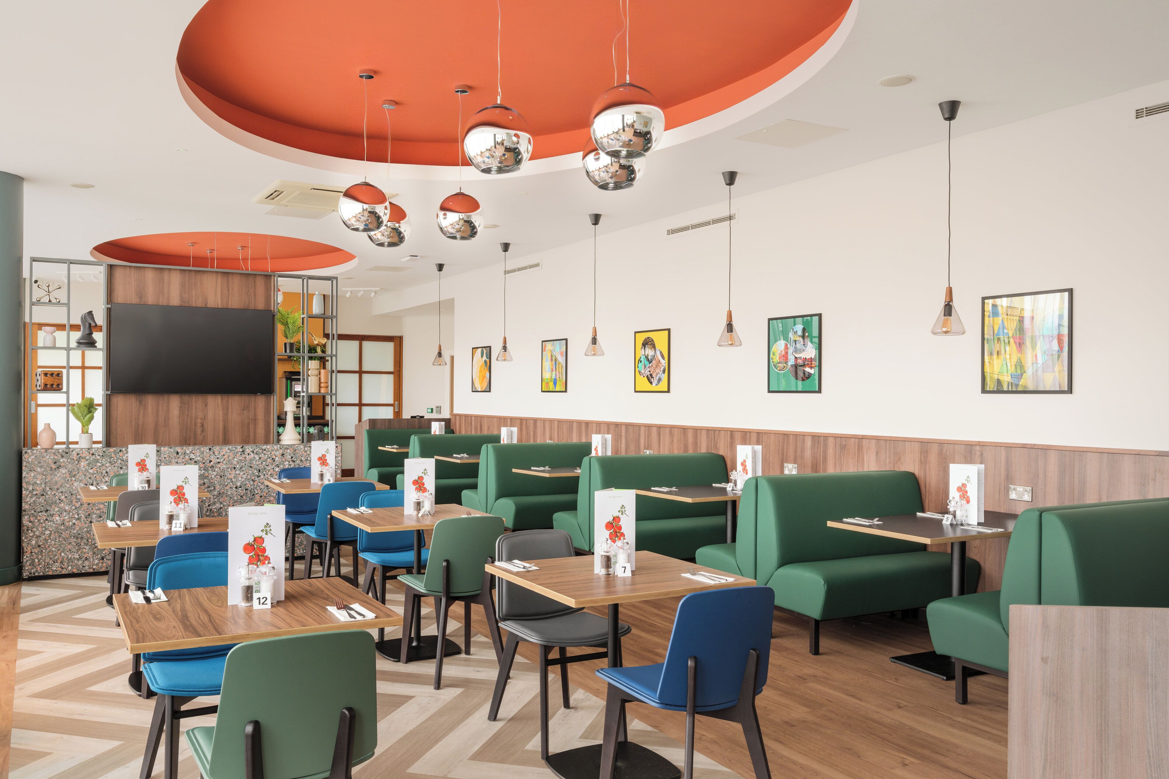 A restaurant with booths and tables, a TV screen, and various wall decorations.