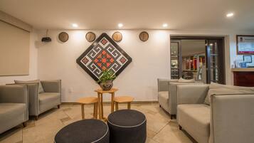 Uma sala de estar moderna com sofás cinza, uma mesa de centro e um objeto decorativo na parede.