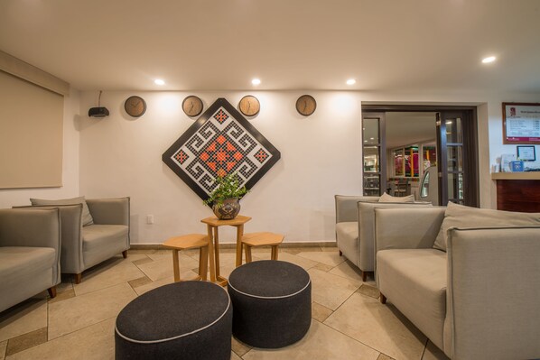 Una sala de estar moderna con sofás grises, una mesa de centro y un elemento decorativo en la pared.