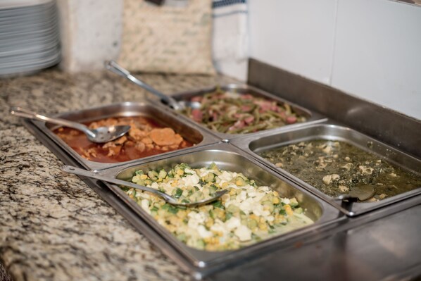 A buffet with various dishes, including a salad, a casserole, and a pasta dish.