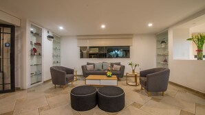 Uma sala de estar moderna com um sofá cinzento, duas poltronas, uma mesa de centro e um aparador de vidro com objetos decorativos.