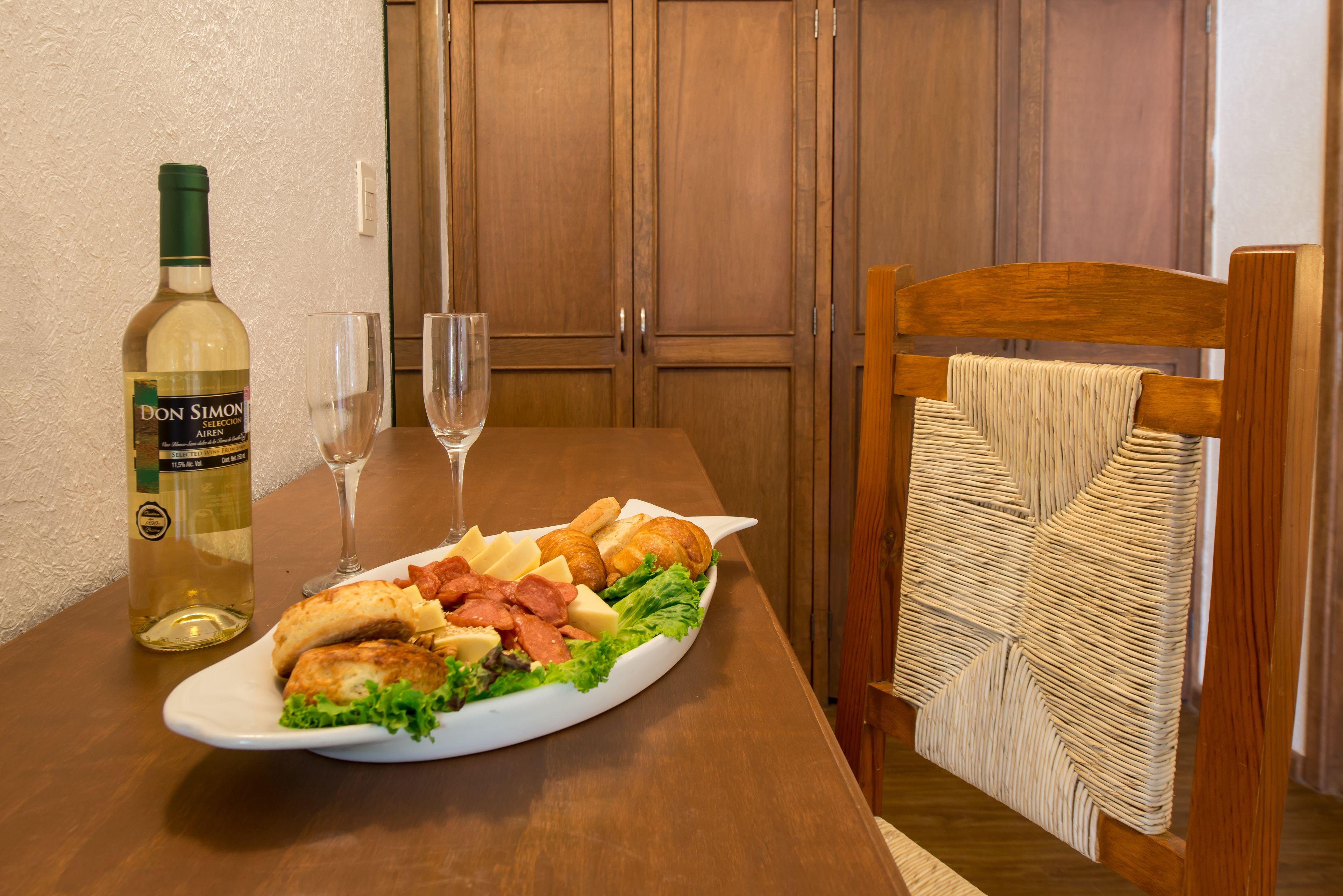 Uma mesa de jantar com um prato de comida, uma garrafa de vinho e dois copos.