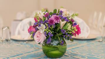 En grøn vase med blomsterarrangement på et bord med blåternet dug.