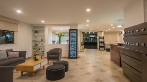 Uma sala de estar moderna com sofá, mesa de centro, pufes e um vaso decorativo.