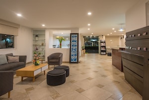 Uma sala de estar moderna com sofá, mesa de centro, pufes e um vaso decorativo.