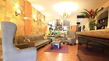 Un vestíbulo amplio con un sofá, sillones, una mesa de centro y un mostrador de recepción.