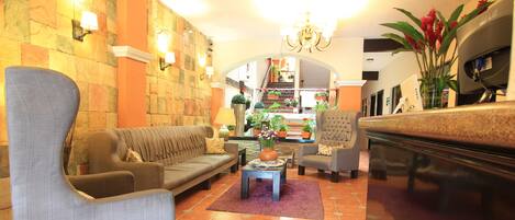 A spacious lobby with a sofa, armchairs, a coffee table, and a reception desk.