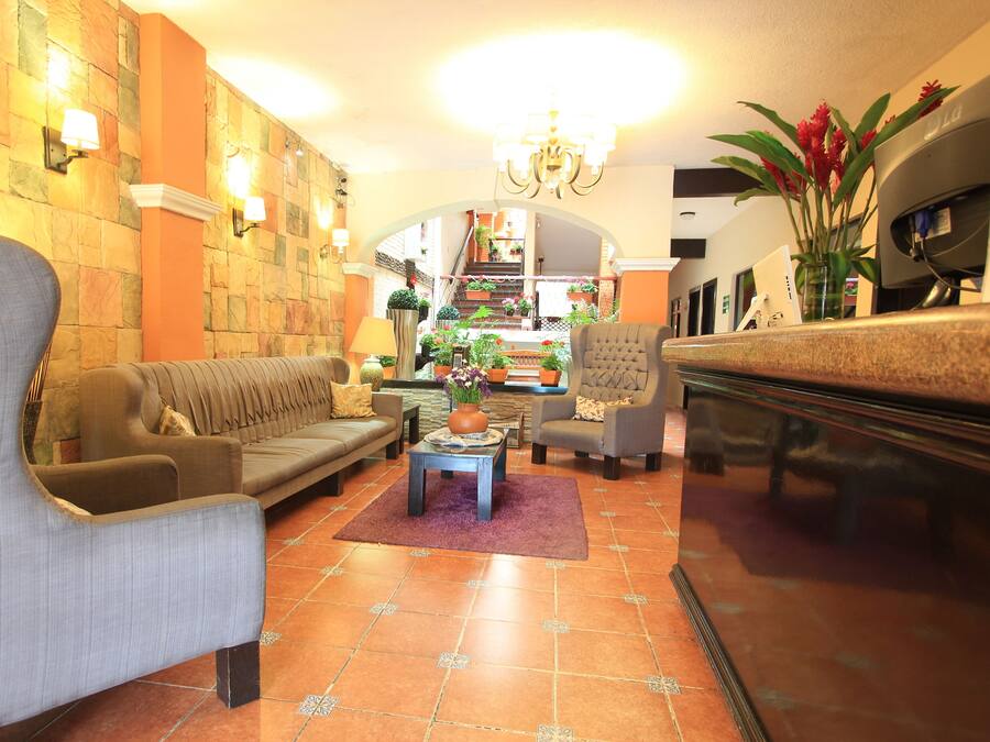 Un vestíbulo amplio con un sofá, sillones, una mesa de centro y un mostrador de recepción.