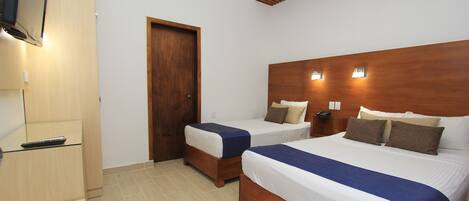 Une chambre d’hôtel avec deux lits, une tête de lit en bois, une télévision et une porte.