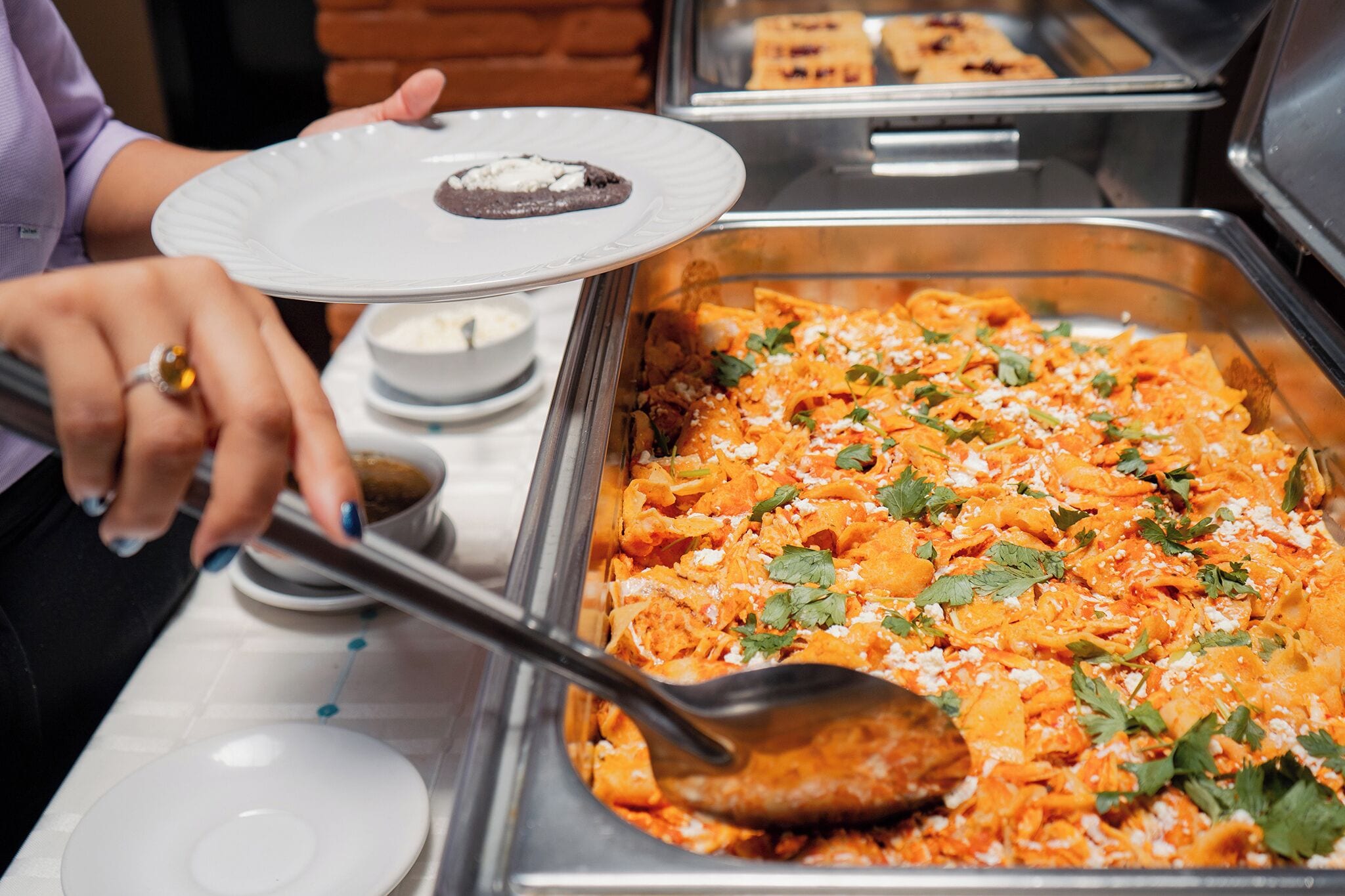 A buffet with a variety of dishes, including a plate with a cookie and a large serving of nachos garnished with cheese and herbs.