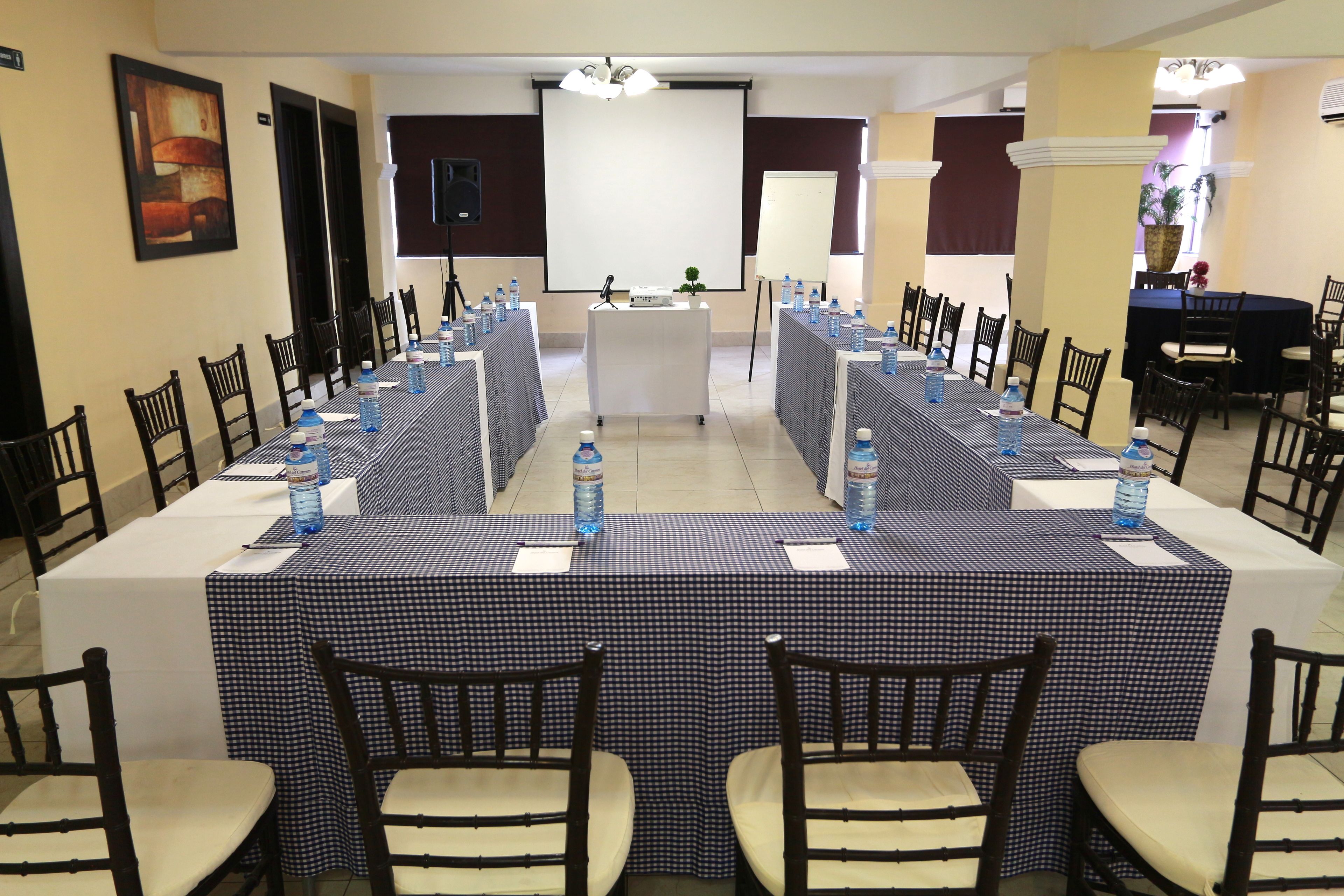 A conference room with a long table, chairs, and a projector screen.