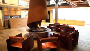 A modern lobby with a central fire feature, seating area, and wooden reception desk. - Scandic Stiklestad (Verdal)