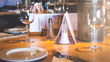 A restaurant table set with plates, cutlery, glasses, and a menu.