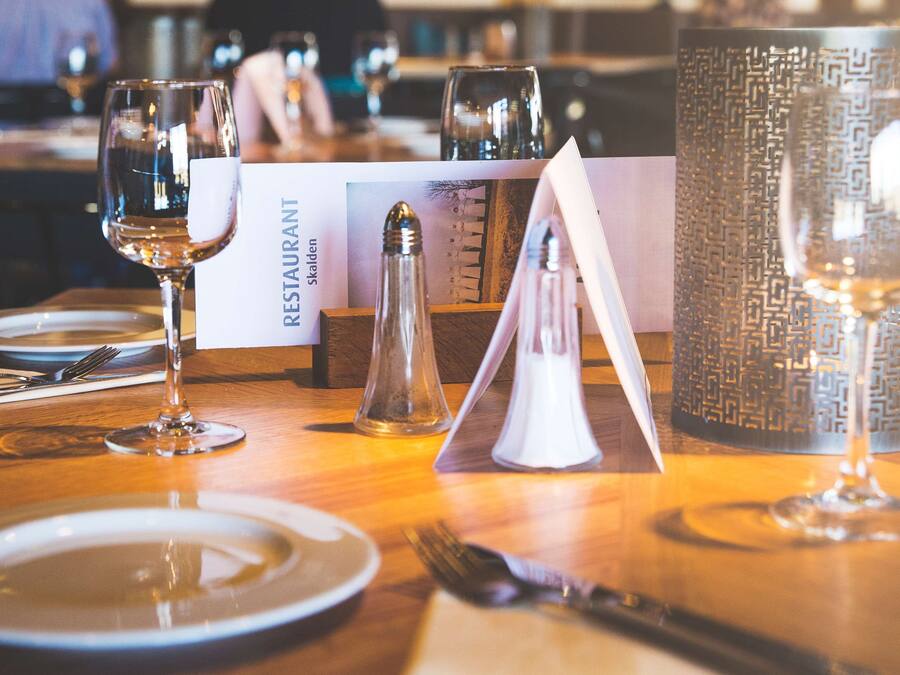 A restaurant table set with plates, cutlery, glasses, and a menu.