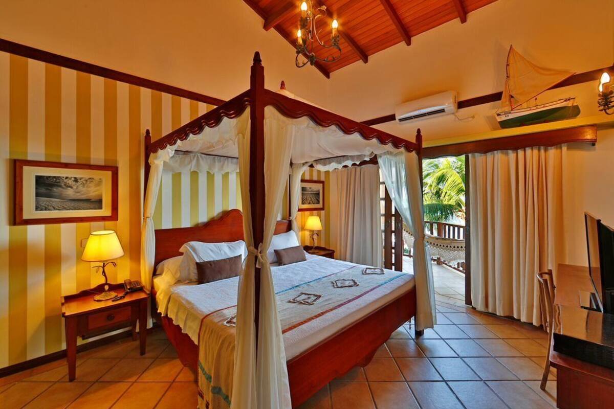 A four-poster bed with a canopy, a wooden headboard, and a bedside table with a lamp.