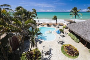 Resort com piscina, espreguiçadeiras e vista para a praia.