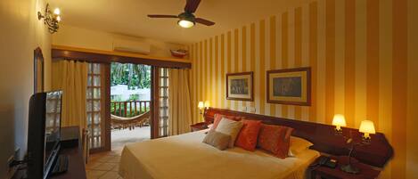A hotel room with a bed, bedside lamps, a ceiling fan, a TV, and a balcony with curtains.
