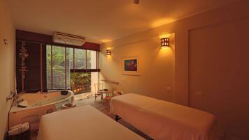 Relax in this serene hotel room featuring a bathtub, two single beds, and a cozy seating area.