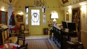 A spacious living room with a high ceiling, ornate ceiling design, a chandelier, a Christmas tree, and a fireplace. - Ai Savoia B&B - Guest House  (Turin)