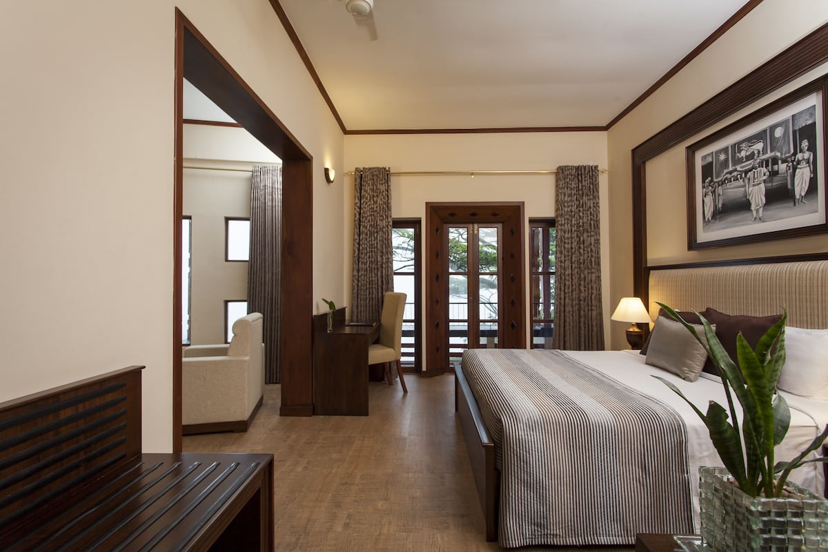A hotel room with a large bed, a desk, a chair, and a view through a door.