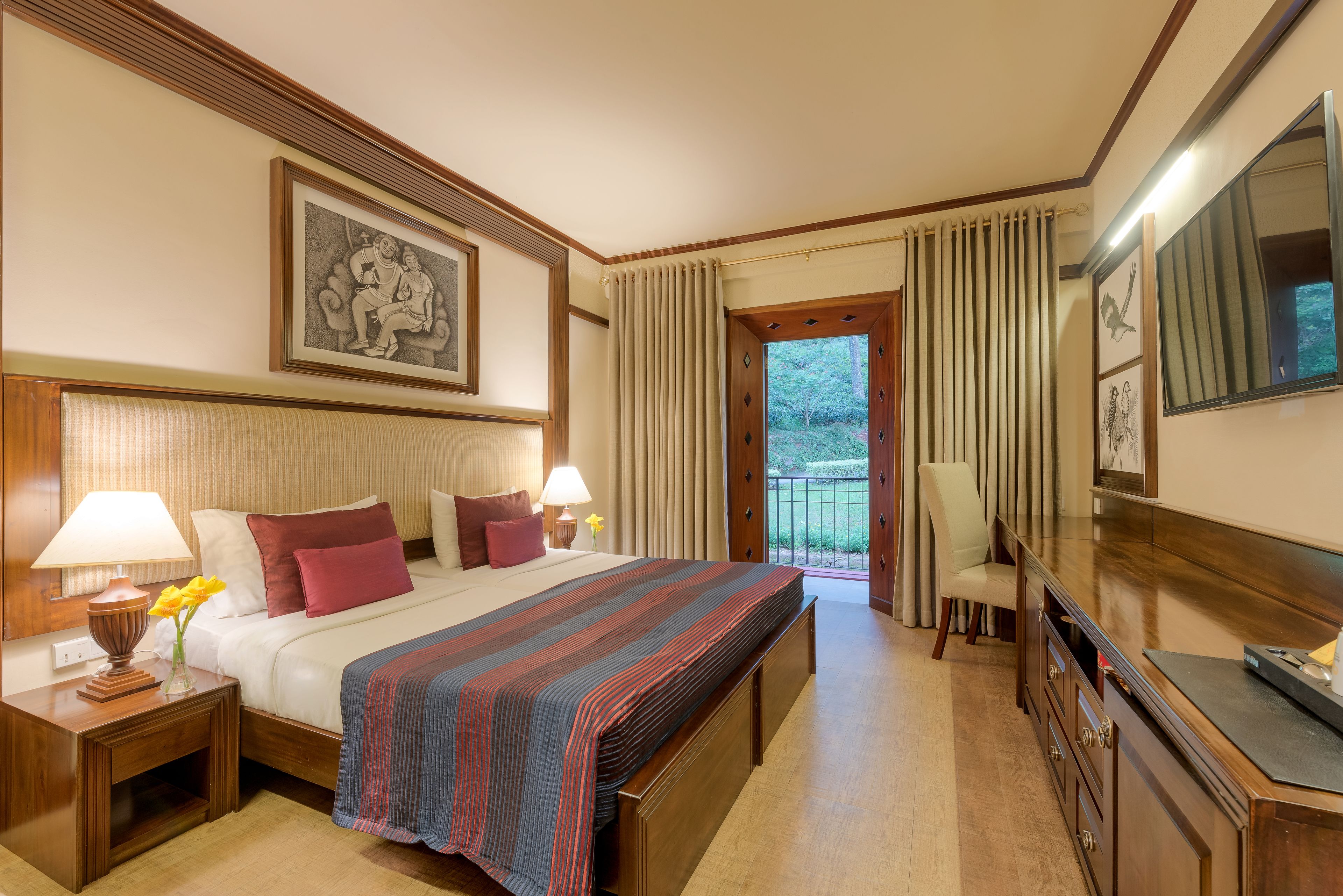 Habitación de hotel con una cama grande, dos mesitas de noche con lámparas, un aparador, un espejo y un balcón con cortinas.