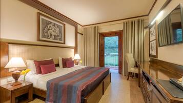 Habitación de hotel con una cama grande, dos mesitas de noche con lámparas, un aparador, un espejo y un balcón con cortinas.