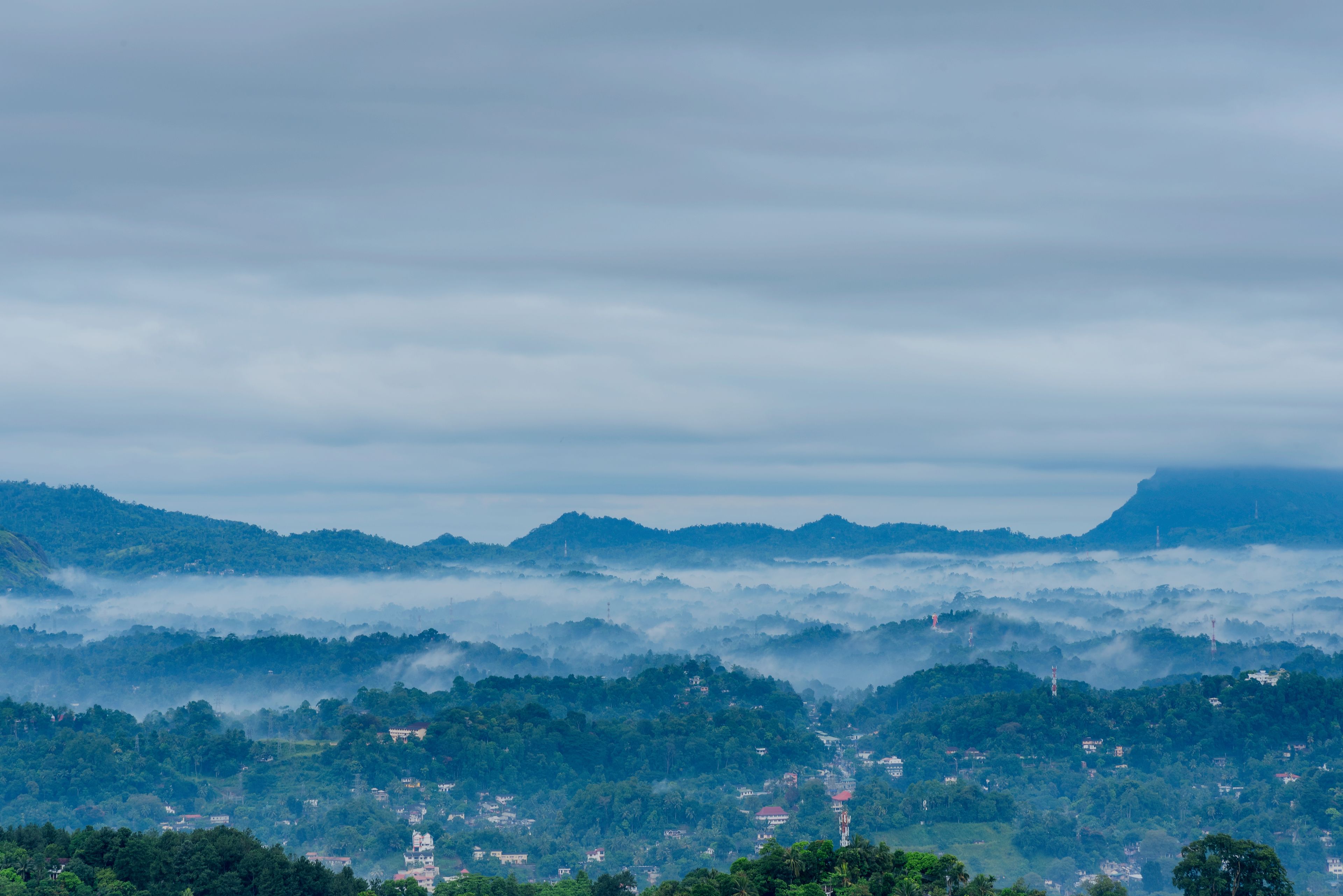A mountainous landscape with scattered buildings and dense forest.