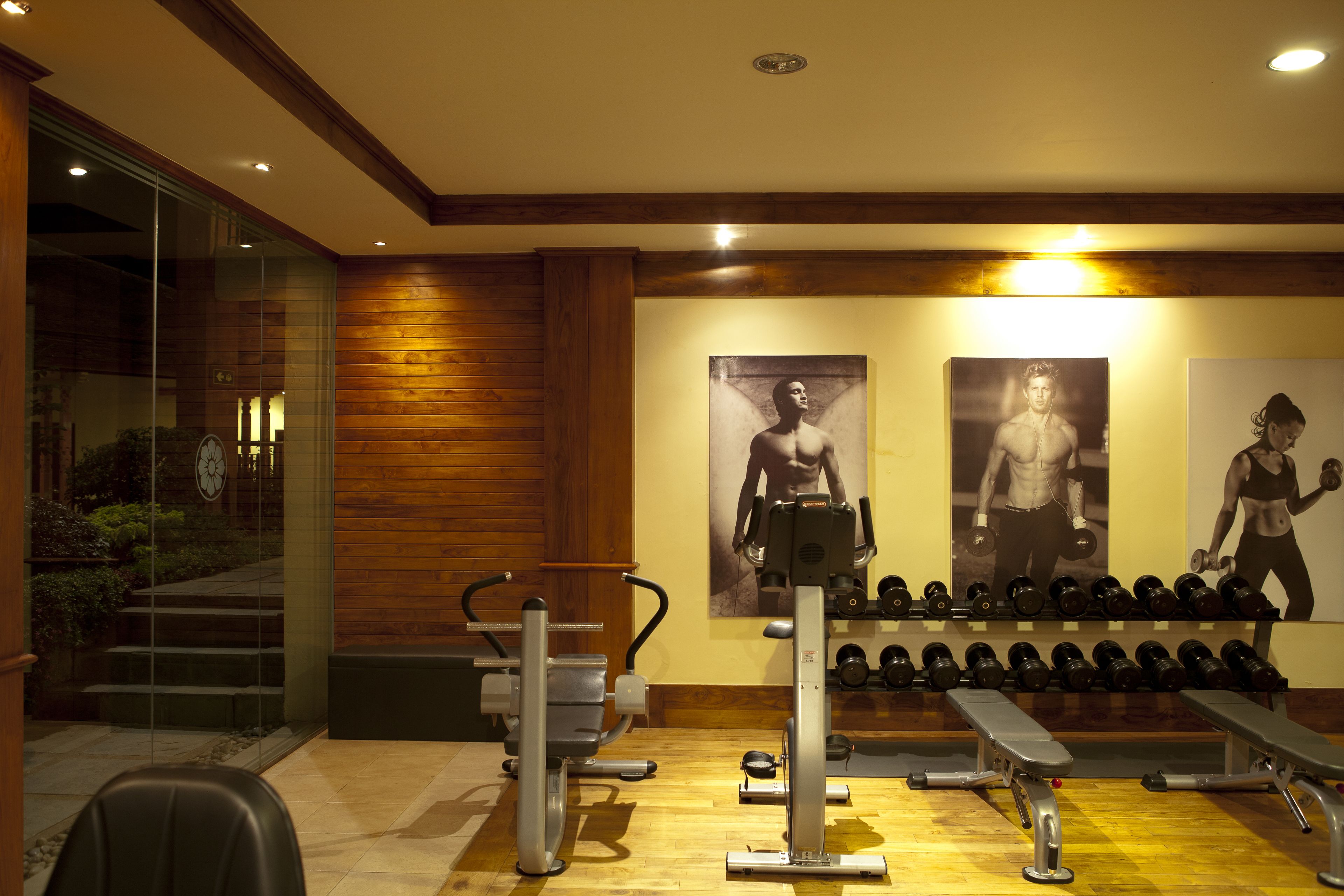 A gym with exercise equipment, benches, and dumbbells.