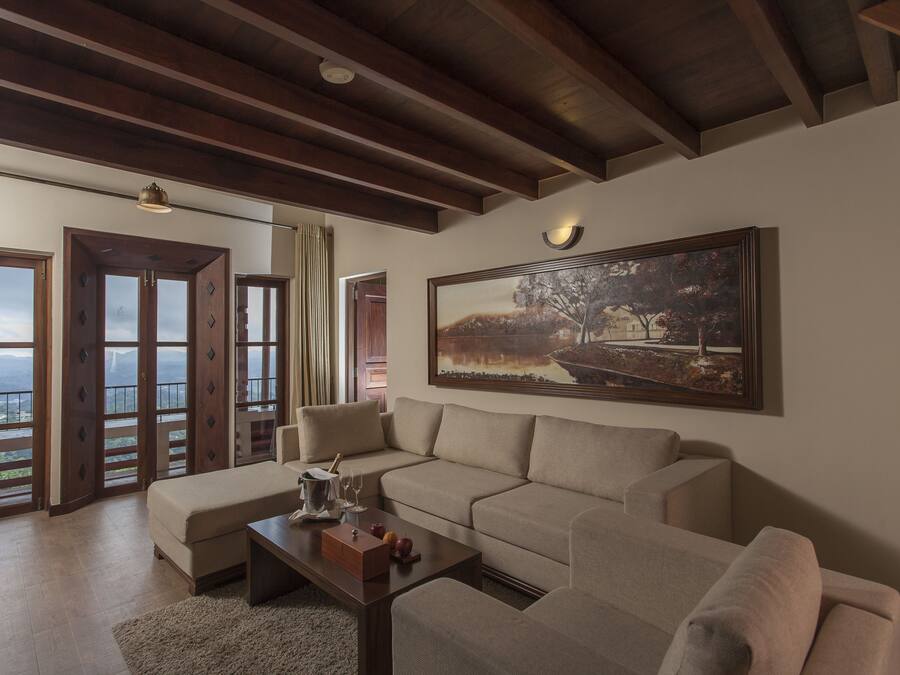 A spacious living room with a beige sofa, a wooden coffee table, and a large painting on the wall.