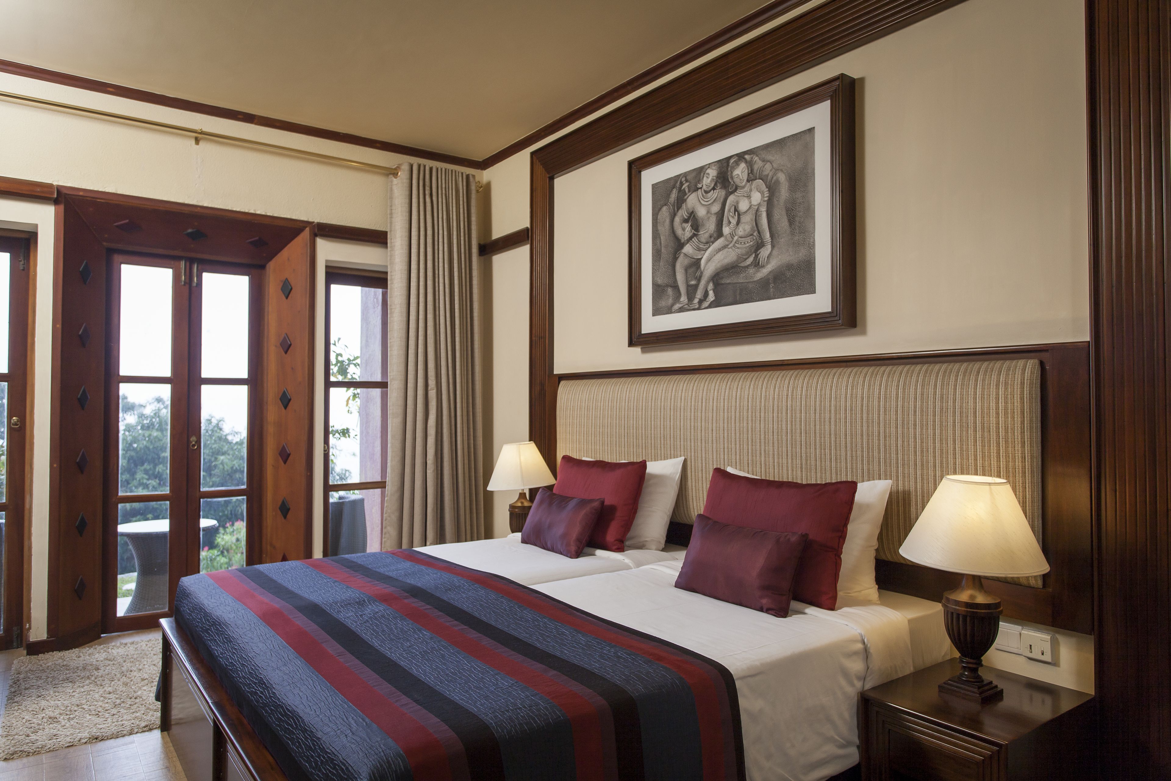 Habitación de hotel con una cama grande, dos mesitas de noche, una lámpara y una obra de arte enmarcada en la pared.