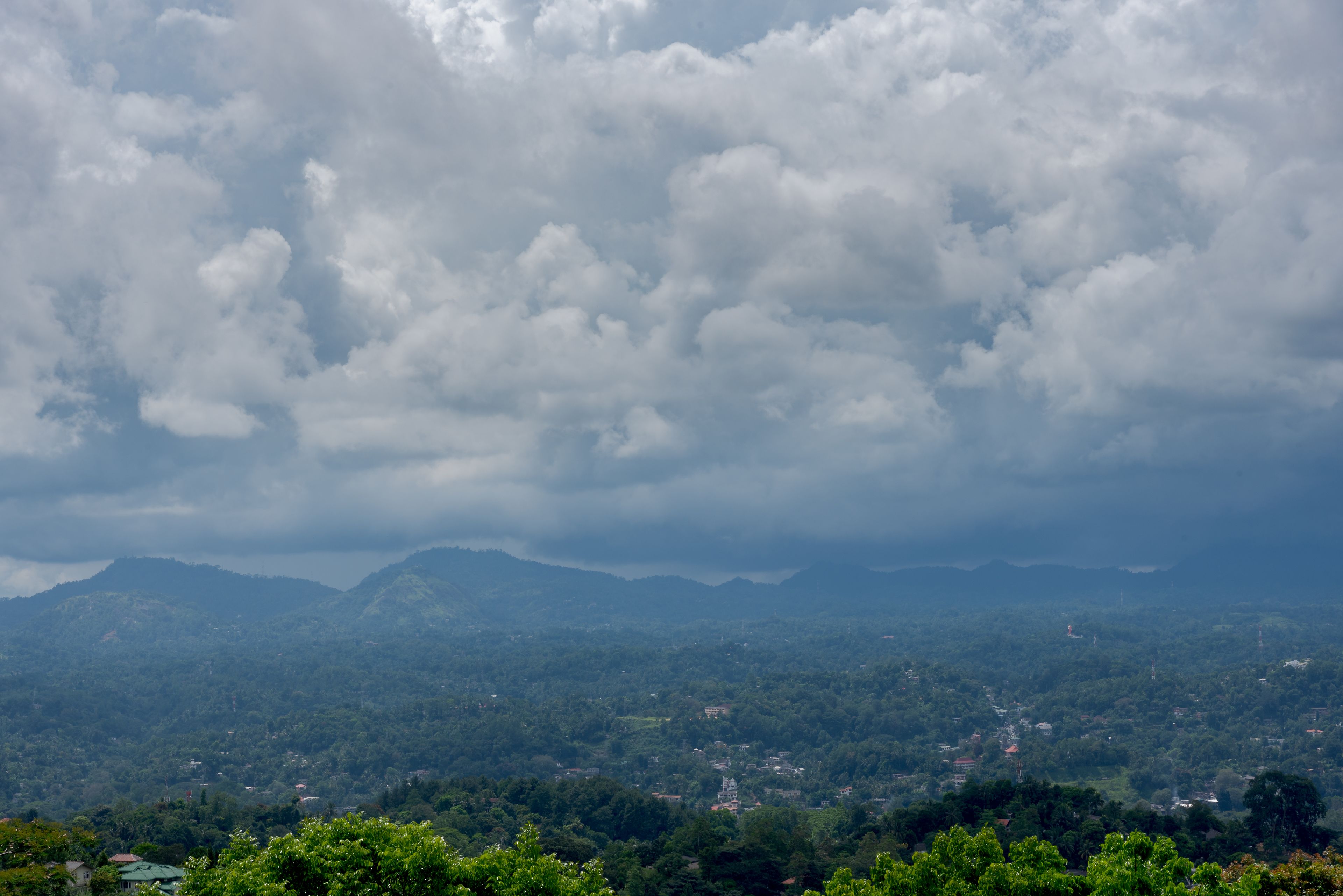 A mountainous landscape with dense greenery and scattered buildings.