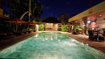 Una piscina al aire libre, sombrillas, sillones reclinables de piscina