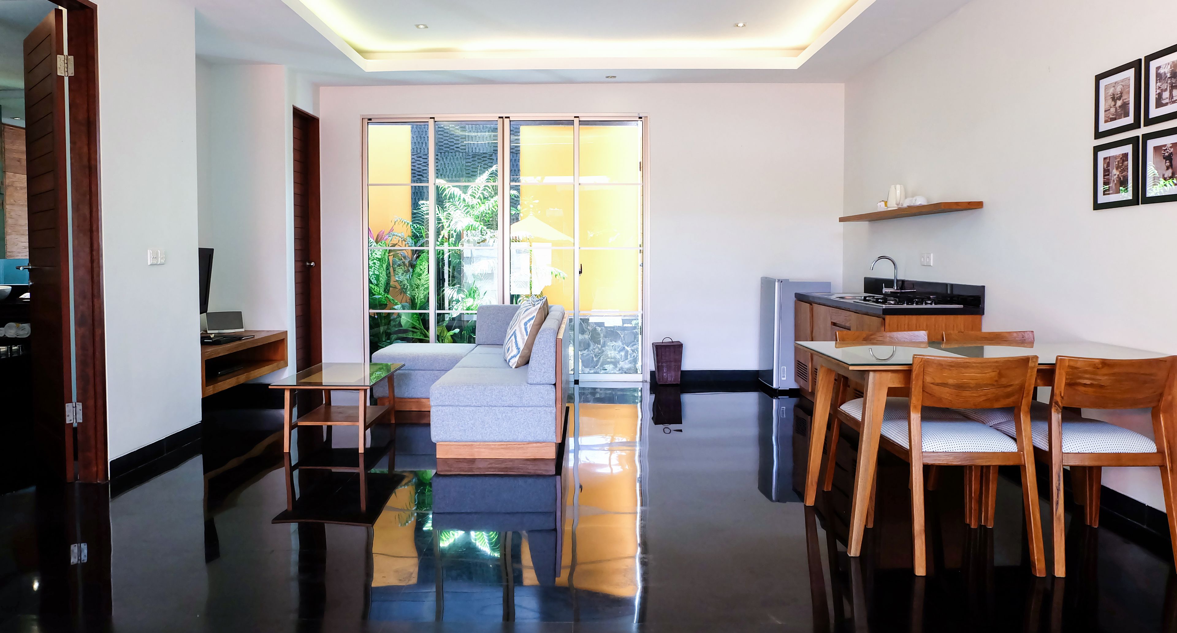 A modern living room with a sofa, a dining table with chairs, and a kitchen area with a sink and stove.