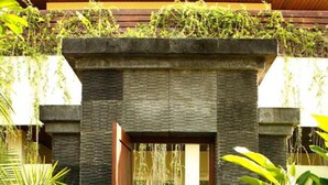 A modern entrance with a stone pathway leading to a wooden door, surrounded by lush greenery. - Sun Island Boutique Villas & Spa Seminyak (Seminyak)