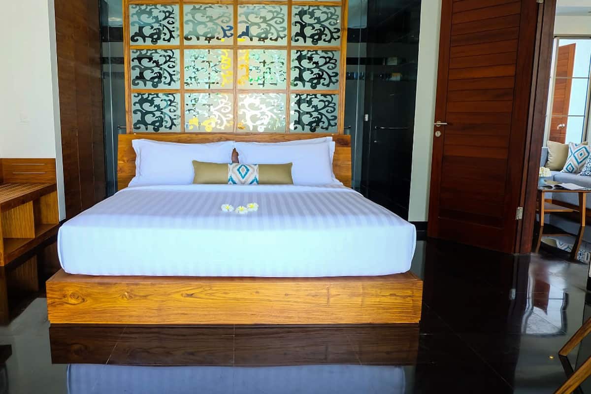 Una habitación de hotel con una cama de madera, un escritorio y un separador de vidrio decorativo.