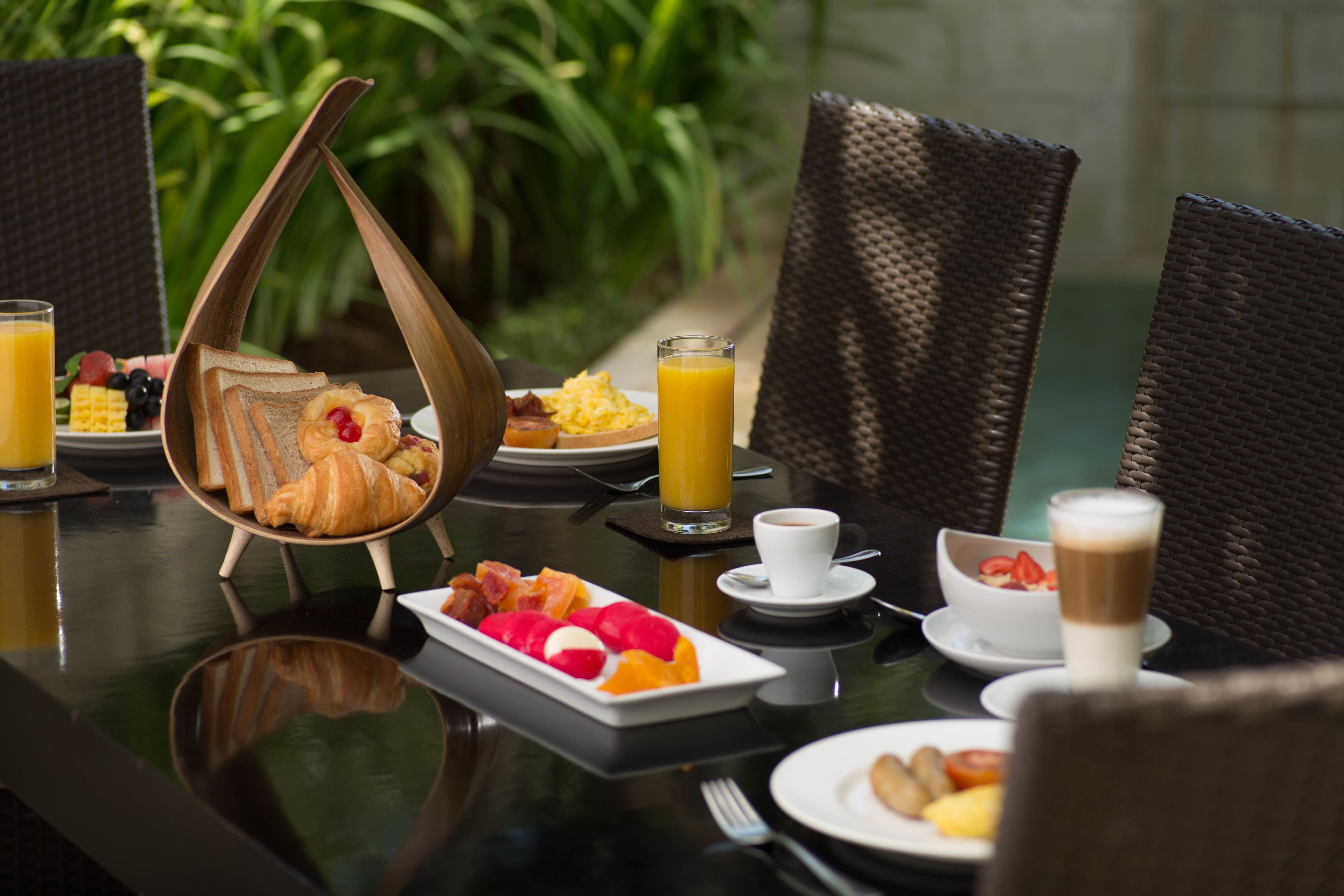 A breakfast table with croissants, fruit, scrambled eggs, and orange juice.