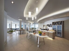 A modern dining area with high ceilings, pendant lighting, and a central serving station. -  Isola di Albarella Hotel Capo Nord (Rosolina)