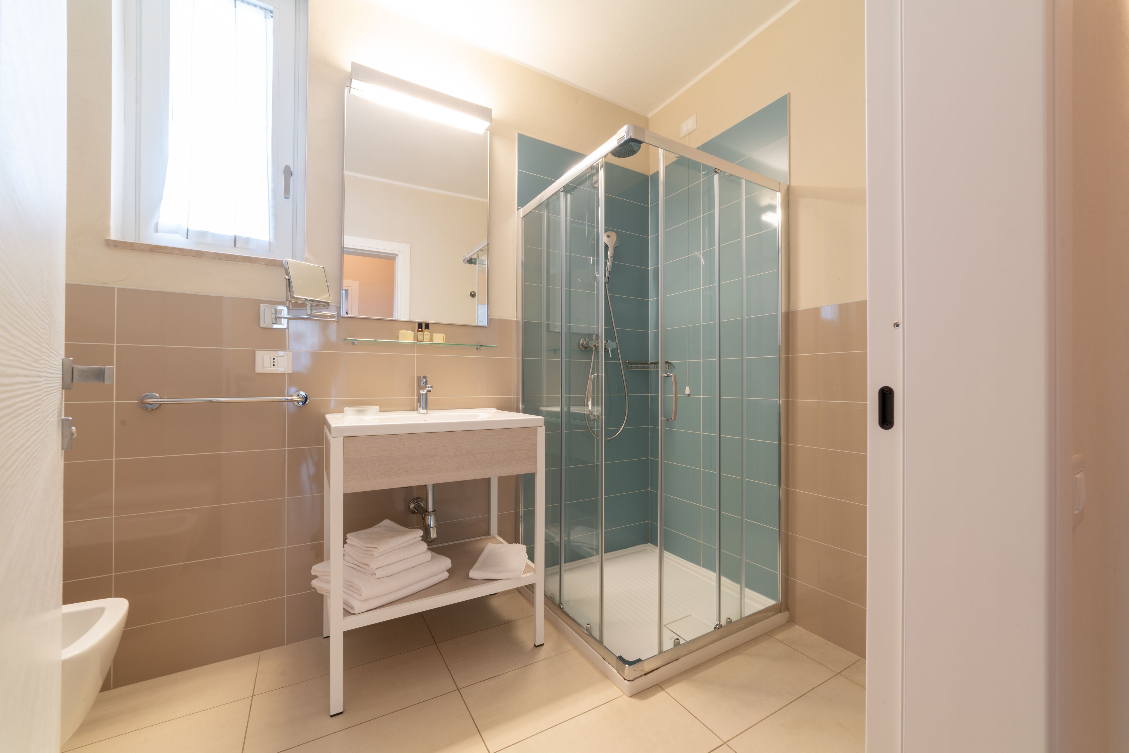 A modern bathroom with a glass-enclosed shower, a white sink, and a towel rack.