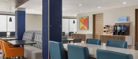 A modern hotel dining area with a mix of seating options including tables, chairs, and a sofa.