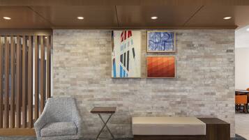 Un vestíbulo moderno con zona de estar, un separador de madera y dos obras de arte abstracto en la pared.