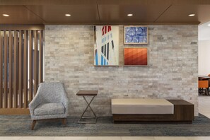 A modern lobby with a seating area, a wooden partition, and two abstract artworks on the wall. - Holiday Inn Express & Suites Huntsville by IHG (Huntsville)