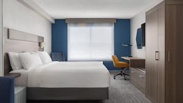 A hotel room with a bed, a desk, a chair, and a wardrobe.