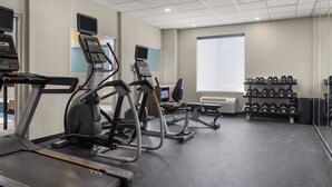 A gym with treadmills, ellipticals, and dumbbells.
