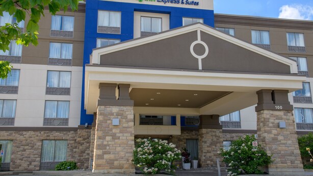A Holiday Inn Express & Suites building with a covered entrance, multiple windows, and a brick facade.