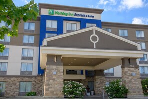 A Holiday Inn Express & Suites building with a covered entrance, multiple windows, and a brick facade. - Holiday Inn Express & Suites Huntsville by IHG (Huntsville)