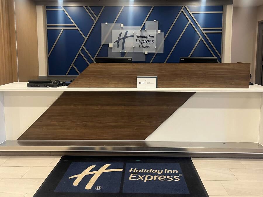 A Holiday Inn Express reception desk with a modern design, including a geometric wall pattern and a wooden accent.